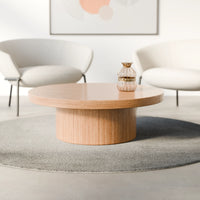 שולחן סלון עגול Syngo עם פלטת פורניר טבעי ובסיס גלילי רחב בעיצוב מינימליסטי