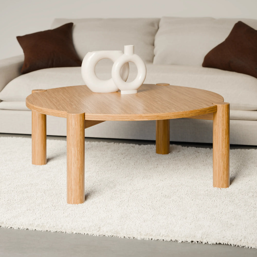 שולחן סלון עגול בעיצוב מודרני עם פלטה מחופה בפורניר טבעי ורגלי עץ מלא עבות.