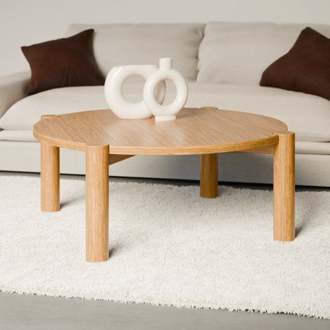 שולחן סלון עגול בעיצוב מודרני עם פלטה מחופה בפורניר טבעי ורגלי עץ מלא עבות.