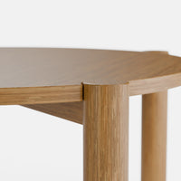 שולחן סלון עגול בעיצוב מודרני עם פלטה מחופה בפורניר טבעי ורגלי עץ מלא עבות.