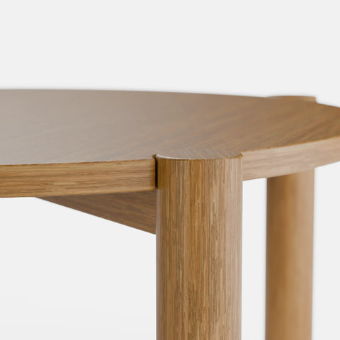 שולחן סלון עגול בעיצוב מודרני עם פלטה מחופה בפורניר טבעי ורגלי עץ מלא עבות.