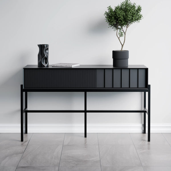 שידה קונסולה מודרנית ואלגנטית בצבע שחור מט, בעלת חזית עם טקסטורה מחורצת ורגלי מתכת דקות, משמשת כפריט אחסון דקורטיבי או כחלק מקולקציית שידות איפור מינימליסטיות.